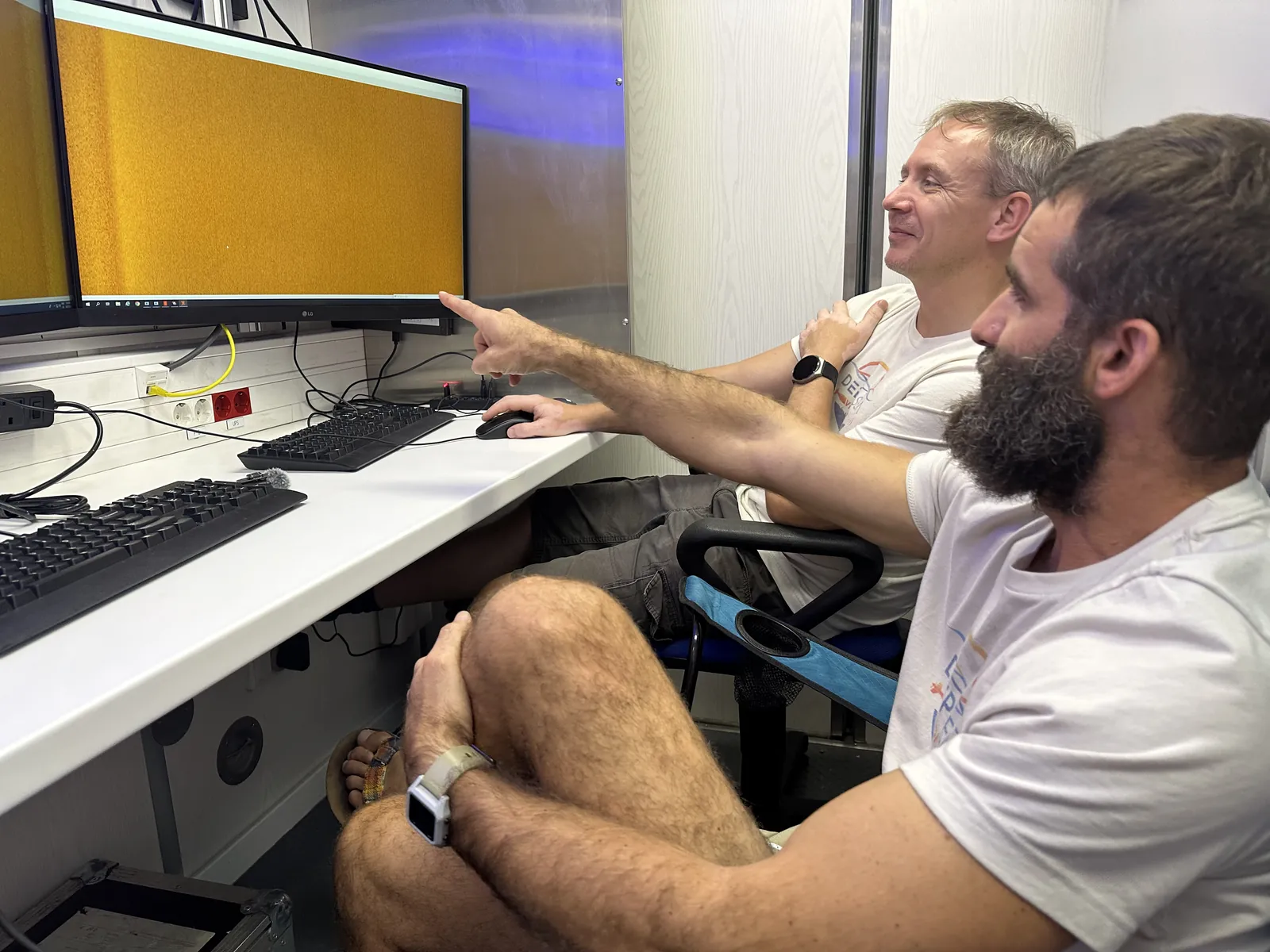Two team members pointing at sonar data on a monitor in the survey control room